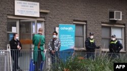 Polisi dan petugas medis berdiri di depan sebuah kompleks hunian di Melbourne, Australia yang terpaksa ditutup 10 Juli 2020, di tengah pandemi Covid-19.