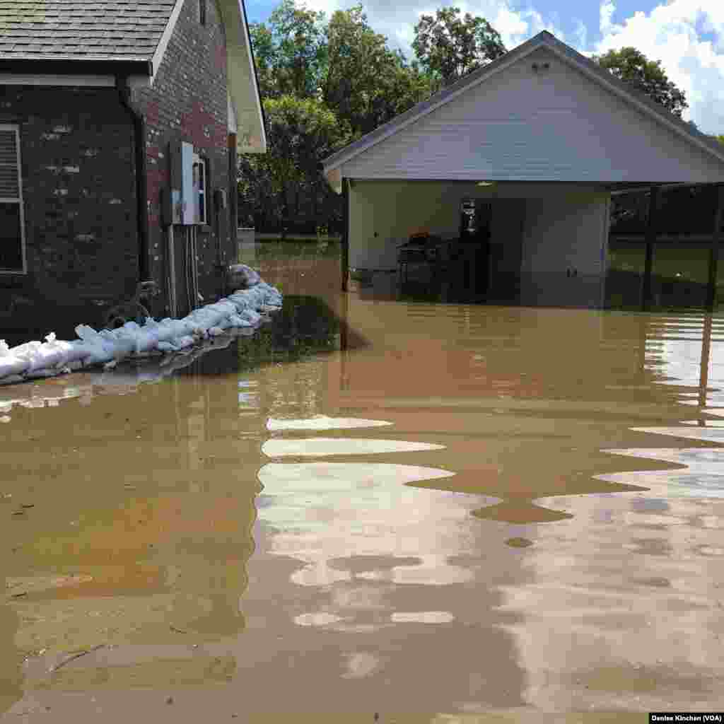Karung-karung pasir digunakan untuk menghalangi banjir masuk ke rumah di St. Amant, Louisiana (18/8).