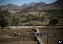 FILE - Afghan villagers take a break after preparing the soil for their poppy seeds in fields in Cham Kalai village in Afghanistan's eastern Nangarhar province, an area which is largely controlled by Taliban, Nov. 12, 2013.