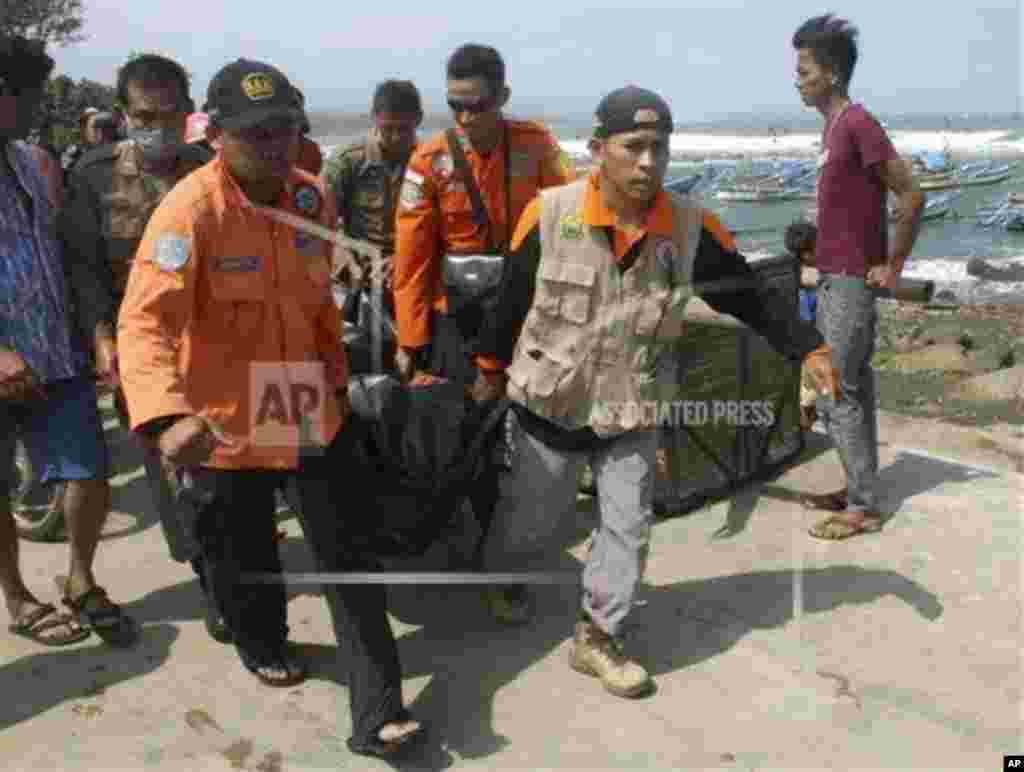 Para petugas penyelamat membawa jenazah korban kapal terbalik di sebuah pantai di Jawa Barat (24/7).