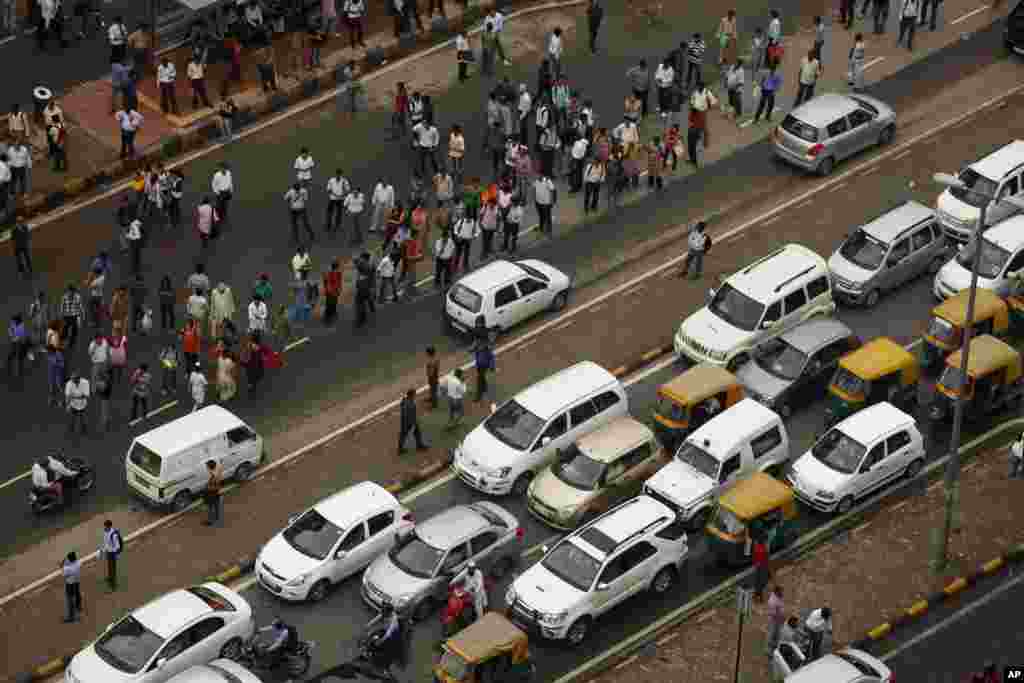 Commuters stand on a busy road outside a Metro station after Delhi Metro rail services were disrupted following power outage in New Delhi, India, July 31, 2012