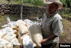 FILE - A farmer carries a bag of provision donated by the United Nations World Food Program (WFP) food reserves, during a distribution of food aid to families affected by the drought, in the village of Orocuina, Honduras, Aug. 28, 2014.