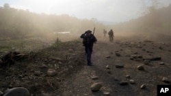 FILE - Counternarcotics officers walk in a clandestine airstrip strewn with boulders, in the Apurimac, Ene and Mantaro River Valleys, or VRAEM, the world's No. 1 coca-growing region, in Junin Peru, Sept. 19, 2014. 