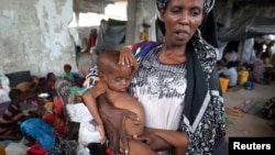 An internally displaced woman holds her malnourished son at a new settlement in Somalia's capital Mogadishu, July 19, 2011. 