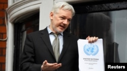 WikiLeaks founder Julian Assange holds a copy of a U.N. ruling as he makes a speech from the balcony of the Ecuadorian Embassy, in central London, Britain, Feb. 5, 2016. 
