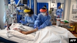 Members of the clinical staff wear personal protective equipment (PPE) as they care for a patient at the Intensive Care unit at Royal Papworth Hospital in Cambridge, on May 5, 2020. - NHS staff wear an enhanced level of PPE in higher risk areas such as cr