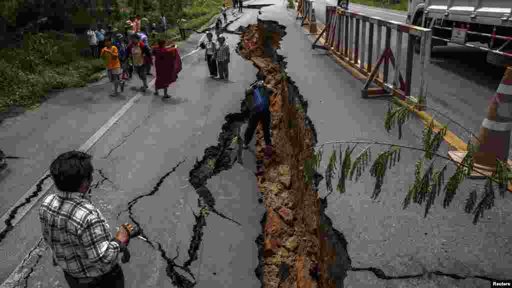 Orang-orang berjalan di jalan raya yang rusak akibat gempa bumi di Chiang Rai, Thailand utara, 6 Mei 2014.
