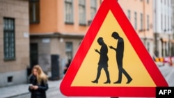 Un panneau interdisant aux piétons de se focaliser à leur téléphone portable quand ils traversent la voie publique, à Stockholm.