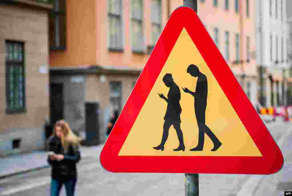 A road sign warns motorists of pedestrians crossing the street while looking at their smartphones&nbsp;near the old town in Stockholm, Feb. 2, 2016.