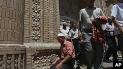 In this Friday, July 10, 2009 file photo, Muslim worshipers come out of a mosque after noon prayers in Kashgar in China's restive Xinjiang province, where new violence erupted on Sunday, July 31, 2011.