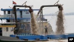 A Cambodian man controls pumps mounted on a ship to dredge sand in the middle of the Mekong River near Phnom Penh, Cambodia, Sunday, Oct. 9, 2011. (AP Photo/Heng Sinith)