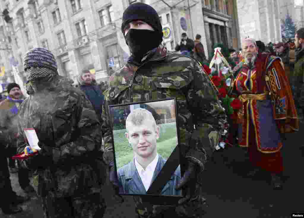 A supporter holds a portrait of Mykhailo Zhyznevsky, an anti-government protester killed during recent rallies, during his funeral in Kyiv, Jan. 26, 2014.&nbsp;