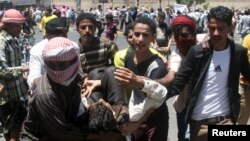 Anti-Houthi protesters carry an injured fellow protester during clashes with Houthi fighters in Yemen's southwestern city of Taiz, March 22, 2015. 