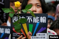 A same-sex marriage supporter holds rose to mourn those who committed suicide due to discrimination during a parliament vote on three draft bills of a same-sex marriage law, outside the Legislative Yuan in Taipei, Taiwan May 17, 2019.