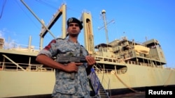 资料照：一名伊朗士兵在苏丹港停泊的伊朗海军最大舰艇“哈格”号旁站岗。（2012年10月31日）