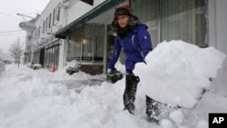 Alisa Riley, shovels snow from a sidewalk in front of a fitness center where she works in Scituate, Massachusetts, Jan. 22, 2014. 