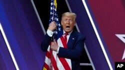 Дональд Трамп обнимает флаг США на конференции CPAC-2020.