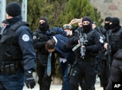FILE - Kosovo police escort Marko Djuric, a Serb official, to a police station in the Kosovo capital of Pristina after he was arrested in the northern Kosovo town of Mitrovica, March 26, 2018.