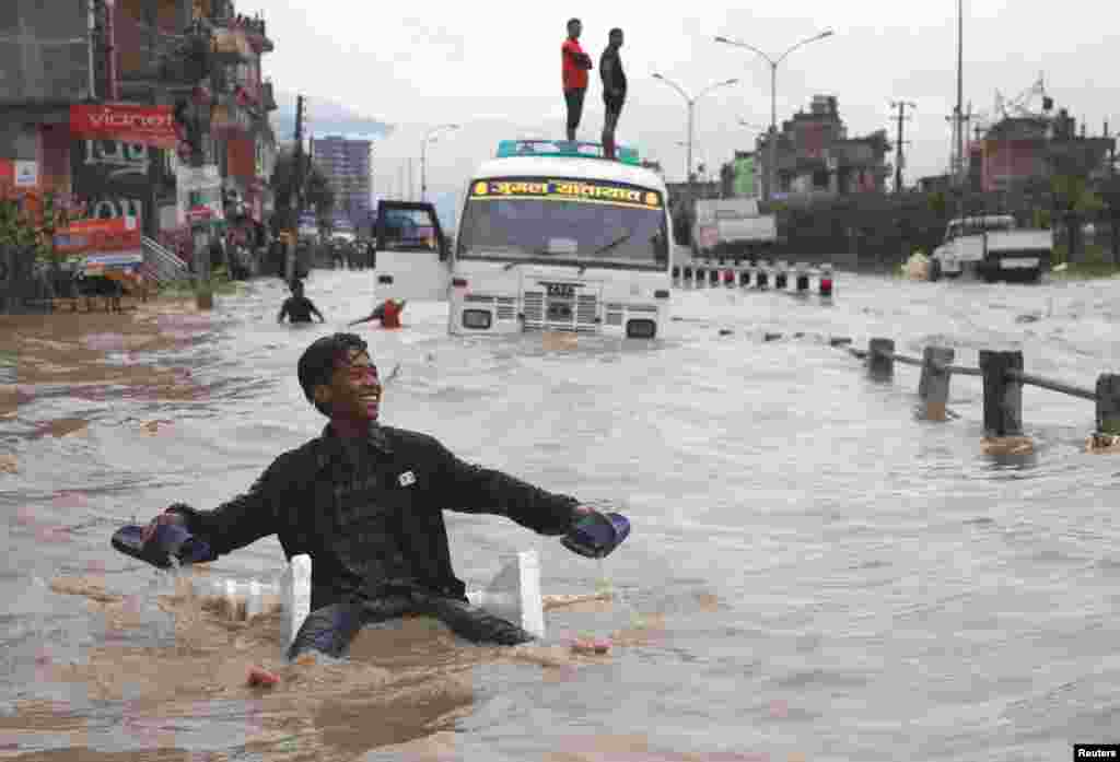 A boy uses an improvised raft to maneuver through the floodwater after incessant rainfall in Bhaktapur, Nepal.