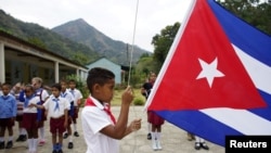 Un garçon élève le drapeau cubain lors d'une cérémonie quotidienne dans une école du village de Santo Domingo, dans la Sierra Maestra, à Cuba, le 2 avril 2018.