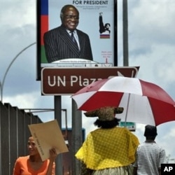 People walk under an election poster of the ruling South West African People's Organization (SWAPO), showing the incumbent President Hifikepunye Pohamba in Katatura, outside Windhoek, 25 Nov 2009