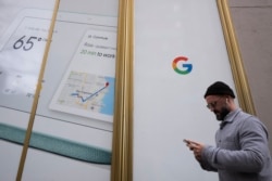 A man using a mobile phone walks past Google offices, Monday, Dec. 17, 2018, in New York. (AP Photo/Mark Lennihan)