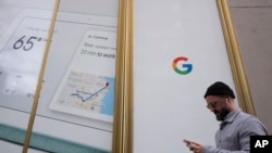 ایک شخص گوگل کے دفتر کے قریب سے گزرتے ہوئے سیل فون پر پیغام بھیج رہا ہے۔ فائل فوٹو