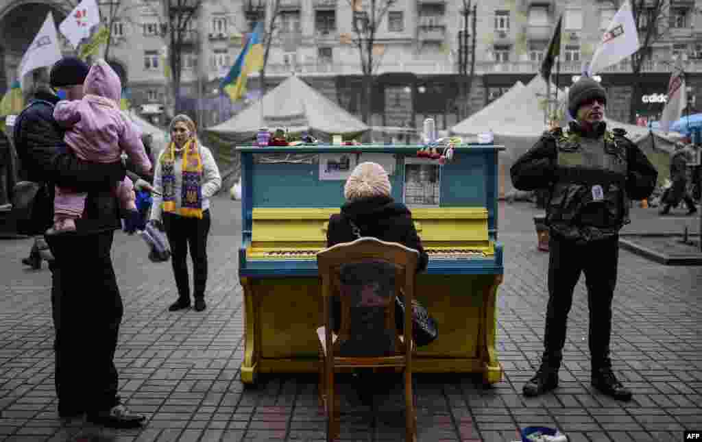 A woman plays a piano in a street near Kyiv&#39;s Independence square, Ukraine. Pro-Russian forces tightened their grip on Crimea as the Kremlin vowed to help restore calm on the restive Ukrainian peninsula and Washington warned of &quot;costs&quot; to Moscow should it order in troops.