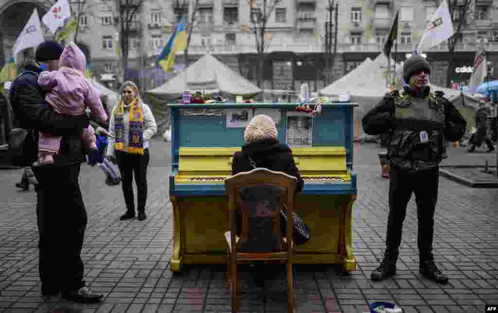 A woman plays a piano in a street near Kyiv's Independence square, Ukraine. Pro-Russian forces tightened their grip on Crimea as the Kremlin vowed to help restore calm on the restive Ukrainian peninsula and Washington warned of "costs" to Moscow should it order in troops.