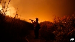 Firefighter Ryan Spencer battles a wildfire as it burns along a hillside toward homes in La Conchita, California, Dec. 7, 2017. 