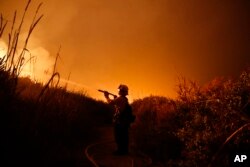 Firefighter Ryan Spencer battles a wildfire as it burns along a hillside toward homes in La Conchita, California, Dec. 7, 2017.