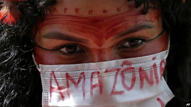 FILE - An Indigenous woman wears a face mask as a precaution against COVID-19 during a protest against Brazilian President Jair Bolsonaro's proposals to allow mining on Indigenous lands, in Brasilia, Brazil, April 20, 2021.