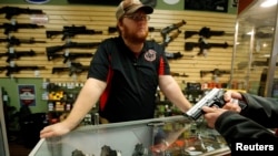FILE - A gun store employee speaks to a customer about the purchase of a 9mm handgun in Bridgeton, Missouri, Nov. 13, 2014.
