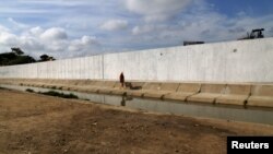 FILE - Ecuadorean workers build a wall along the border between Peru and Ecuador in Aguas Verdes, Peru, June 8, 2017. 