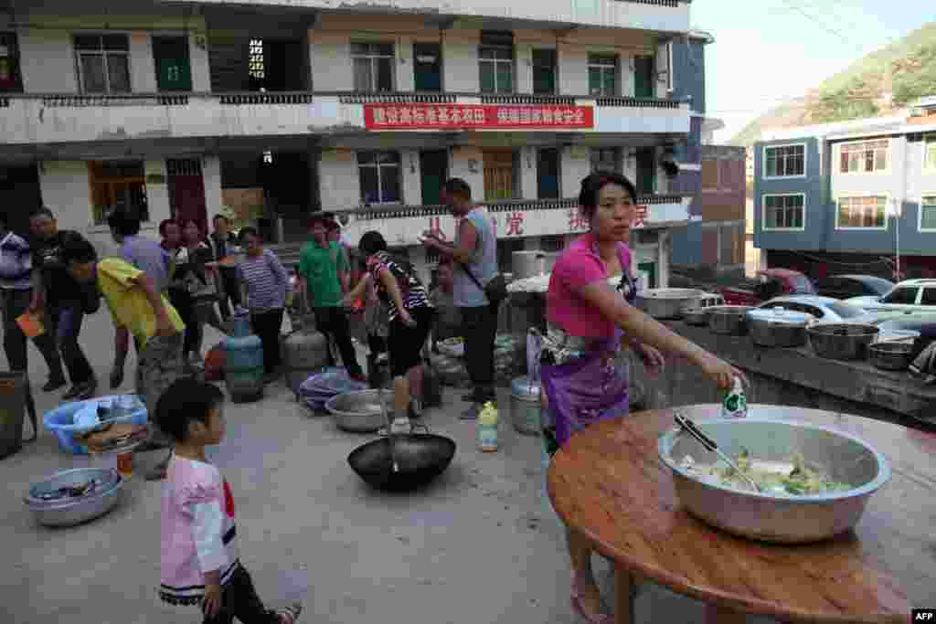 Residents gather to cook a meal in Yiliang, southwest China's Yunnan province following two shallow quakes that struck the remote and mountainous border area of Yunnan and Guizhou province of southwest China, Sept. 7, 2012.
