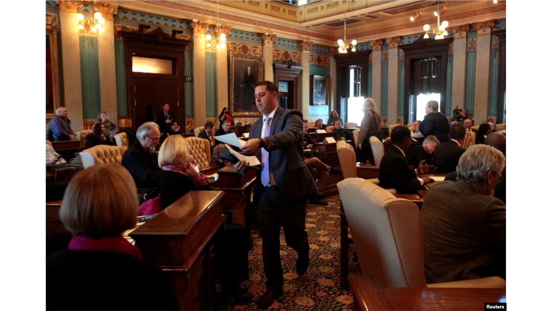 FILE - Ballots are passed out to 16 Electors on the Michigan Senate floor for them to cast their formal votes for the president and vice president of the United States in Lansing, Michigan, Dec. 19, 2016.