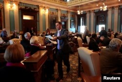 FILE - Ballots are passed out to 16 Electors on the Michigan Senate floor for them to cast their formal votes for the president and vice president of the United States in Lansing, Michigan, Dec. 19, 2016.