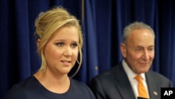 Actress Amy Schumer speaks while her distant cousin, Senator Chuck Schumer watches during a news conference in New York, Aug. 3, 2015. The Schumers are teaming up to try and enact gun control regulations. 