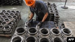 FILE - An employee works on transmission parts at a factory in Lianyungang in China's eastern Jiangsu province, Sept. 14, 2018. 