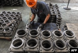 FILE - An employee works on transmission parts at a factory in Lianyungang in China's eastern Jiangsu province, Sept. 14, 2018.