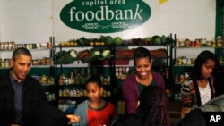 美国总统奥巴马的全家2011年在感恩节前夕在华盛顿一个为穷人提供食物的食品银行帮助发放食物
