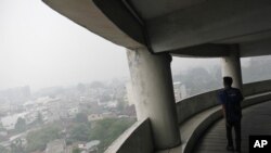 A man walks in a building as haze from wildfires blanket the city Medan, North Sumatra, Indonesia, Tuesday, Oct. 6, 2015. 