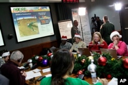 Volunteers take phone calls from children asking where Santa is and when he will deliver presents to their house, during the annual NORAD Tracks Santa Operation, at the North American Aerospace Defense Command, or NORAD, at Peterson Air Force Base, in Col