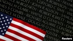 Una bandera descansa junto a los nombres grabados en el Monumento a los héroes de la Guerra de Vietnam en Washington D.C.