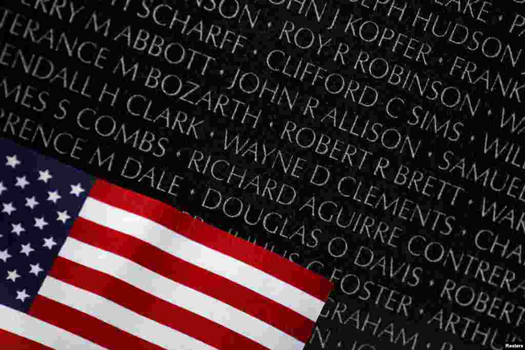 美国华盛顿越战纪念碑： 黑色花岗岩上阵亡将士姓名及悼念者安放的国旗