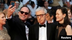 FILE - A guest takes a selfie with director Woody Allen (C) and his wife Soon-Yi Previn as they arrive on the red carpet at the 68th Cannes Film Festival in Cannes, southern France.
