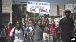 A demonstrator shouts as he carries a sign reading in Creole 'Minusta and Cholera are twins' during a protest in Port-au-Prince, Haiti, 18 Nov 2010