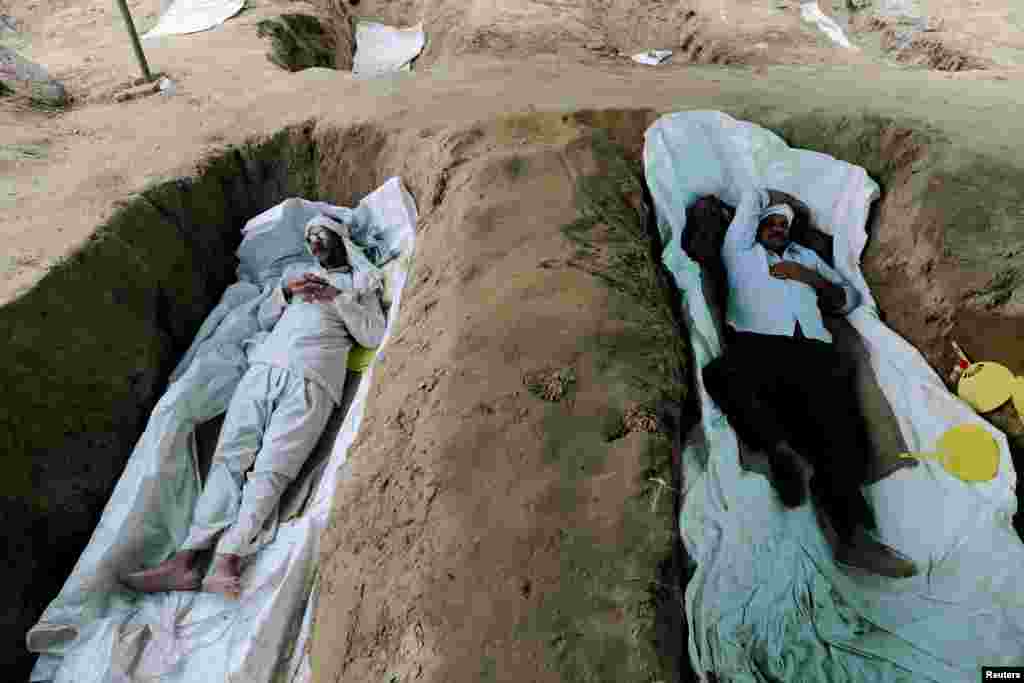 Farmers lie in graves that they dug in a protest against the farms laws, at Mandola village in Ghaziabad, India.