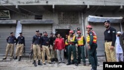 Policemen and rescue workers gather outside a building where unidentified gunmen killed police cadets in Lahore on July 12, 2012. 