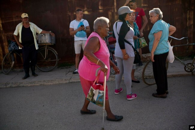 FILE - Pura Castell walks to a government-run butcher shop to buy chicken, after failing to find chicken the previous day, in Bauta, Cuba, April 12, 2019. A neighbor informed her that chicken had arrived at the government store that distributes almost free monthly food rations.